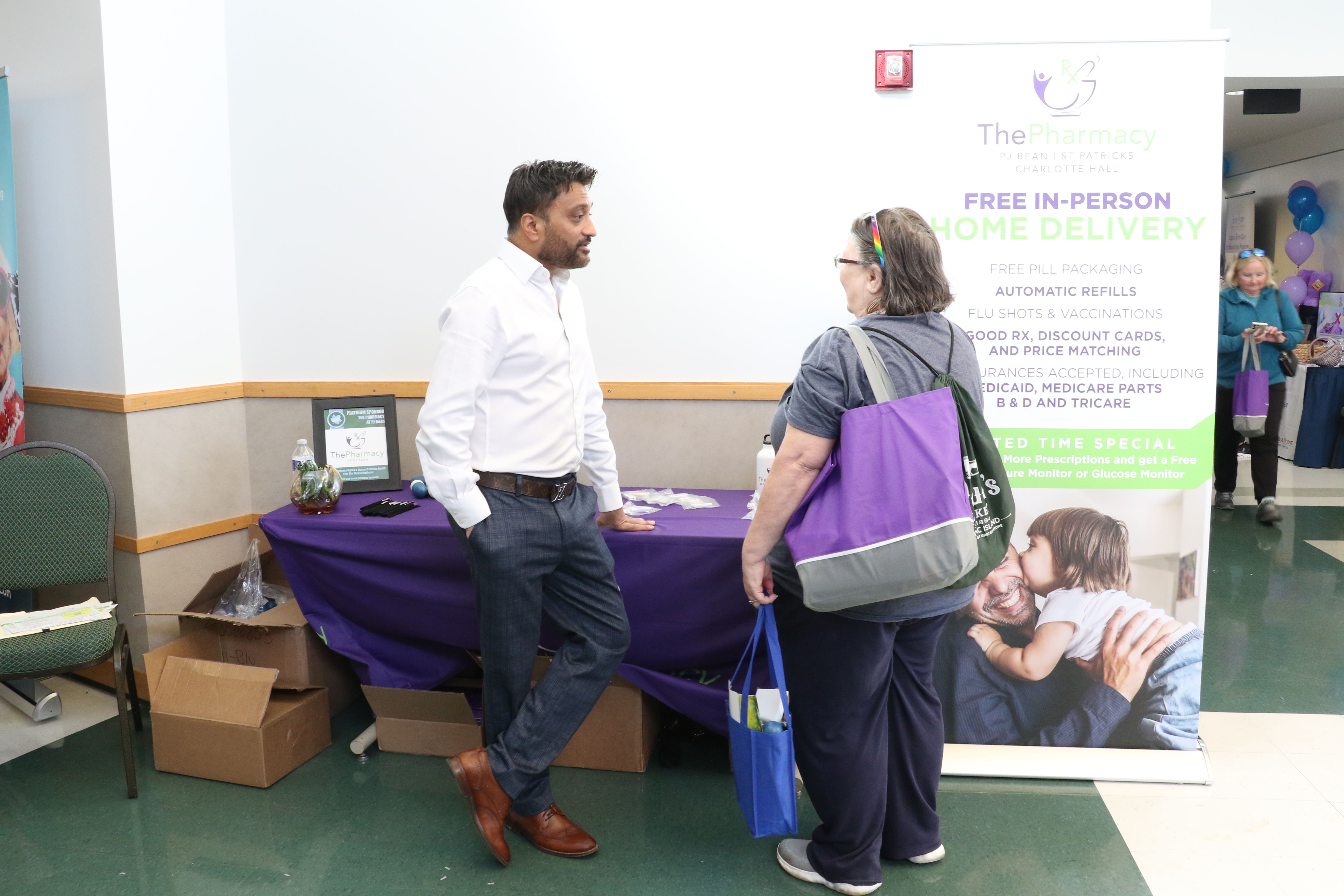 A person conversating with another person in front of the Pharmacy table