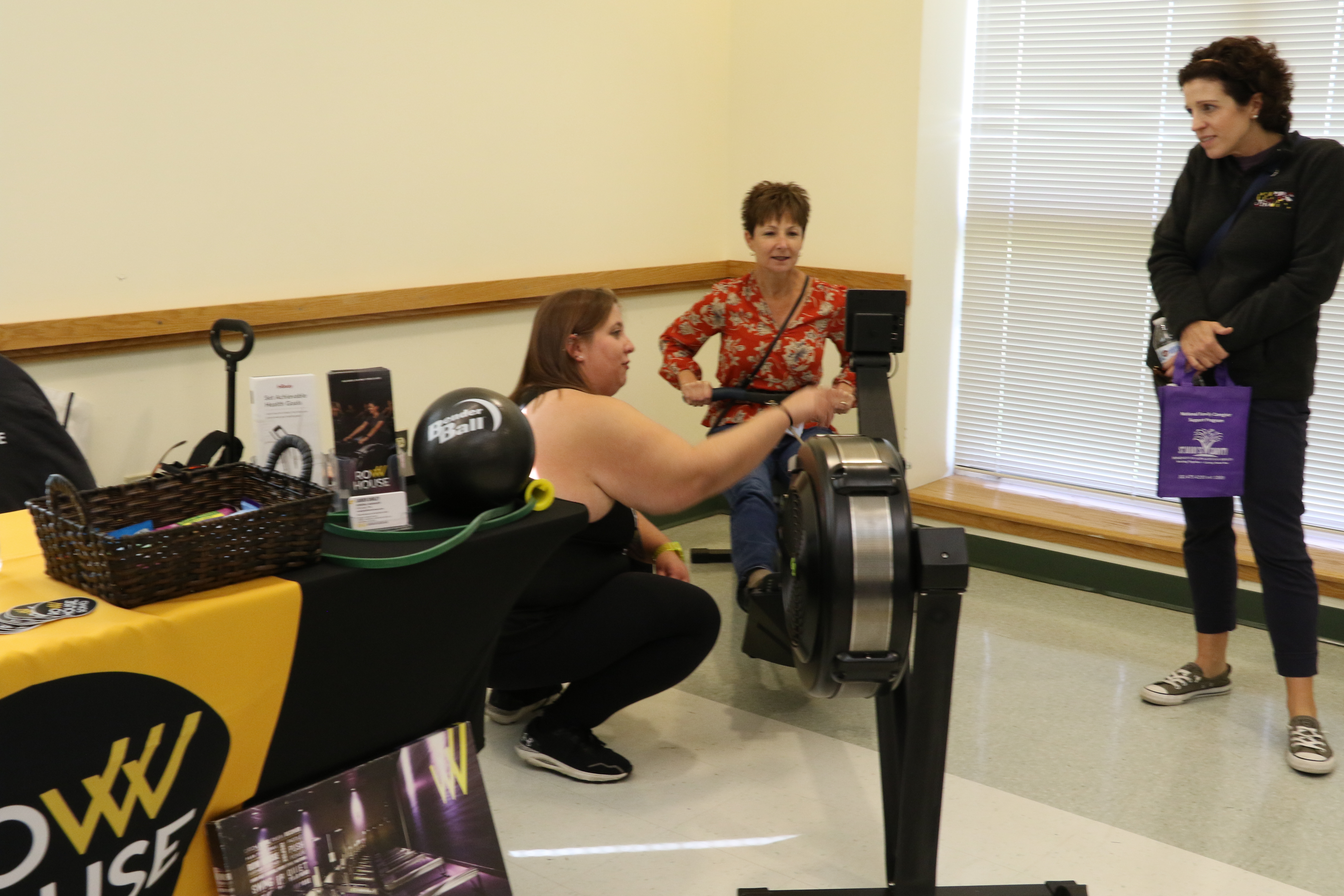 A person using an excercise machine while two other people watch